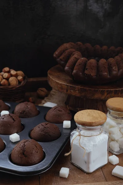 Bolo de chocolate e pequenos cupcakes com nozes na mesa rústica — Fotografia de Stock