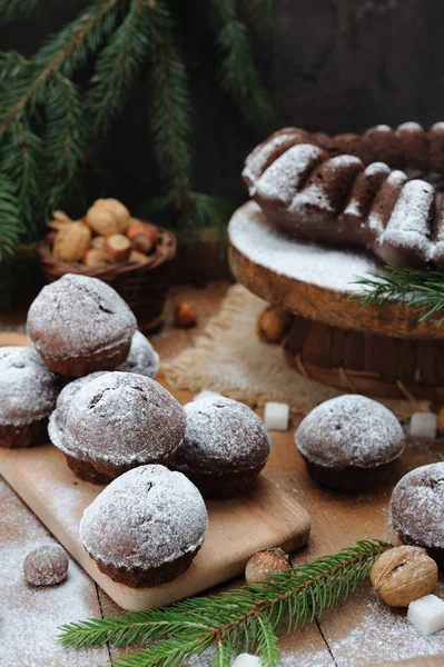 Bolo de chocolate e pequenos cupcakes com decorações de férias na mesa rústica — Fotografia de Stock