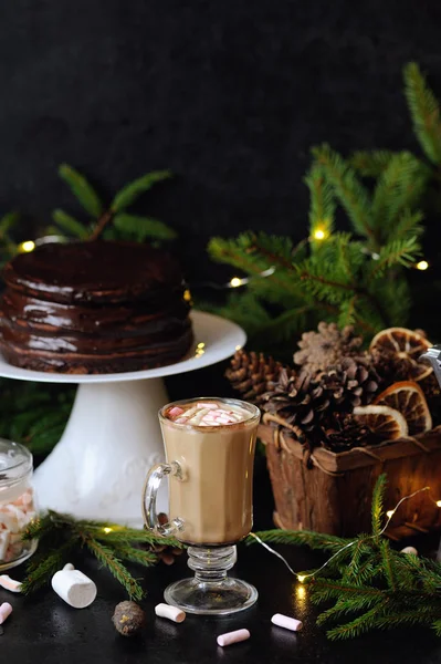 Cup of hot cocoa with mini marshmallows, chocolate cake and Christmas decorations on black background — Stock Photo, Image