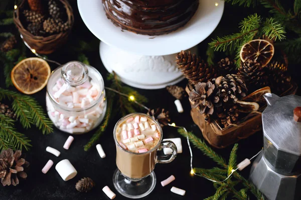 Cup of hot cocoa with mini marshmallows, chocolate cake and Christmas decorations on black background — Stock Photo, Image