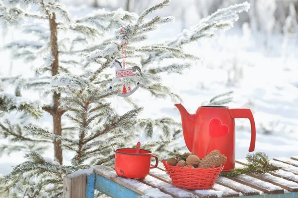 Red kettle and cup with hot tea outdoor in winter day