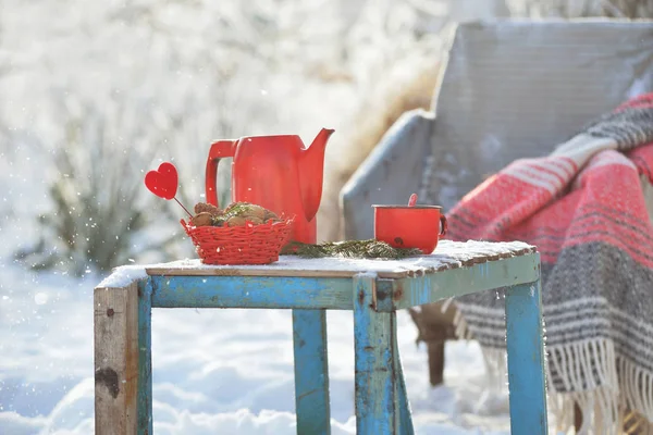 Red kettle and cup with hot tea outdoor in winter day