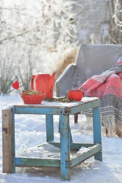Red kettle and cup with hot tea outdoor in winter day