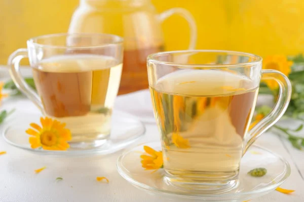 Лекарственные свежие цветы и травяной чай из календулы в чайнике и чашки — стоковое фото