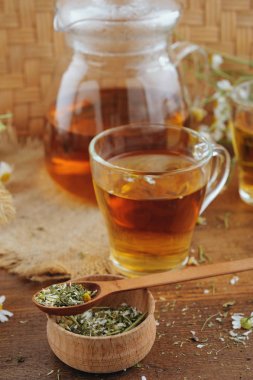 Bitkisel papatya çayı, bal ve rustik ahşap masaya taze çiçek