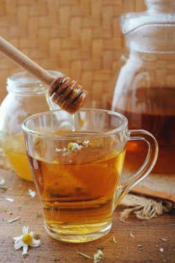 Bitkisel papatya çayı, bal ve rustik ahşap masaya taze çiçek