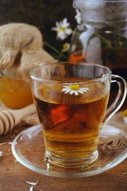 Bitkisel papatya çayı, bal ve rustik ahşap masaya taze çiçek