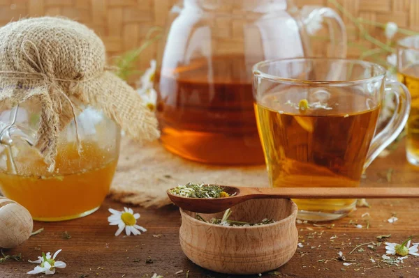 Herbal chamomile tea, honey and fresh flowers on rustic wooden table