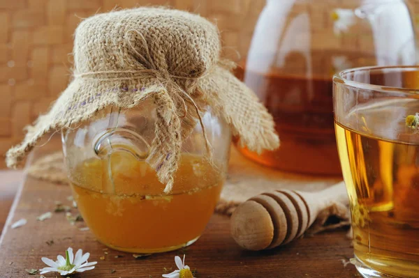 Växtbaserade kamomillte, honung och färska blommor på rustika träbord — Stockfoto