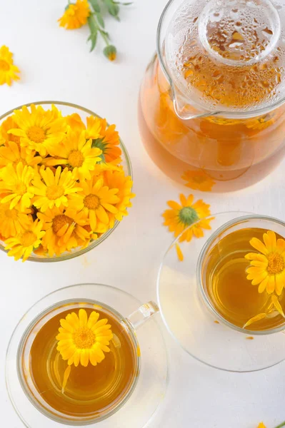 Two cups of healthy marigold tea and calendula flowers in a glass bowl — Stock Photo, Image