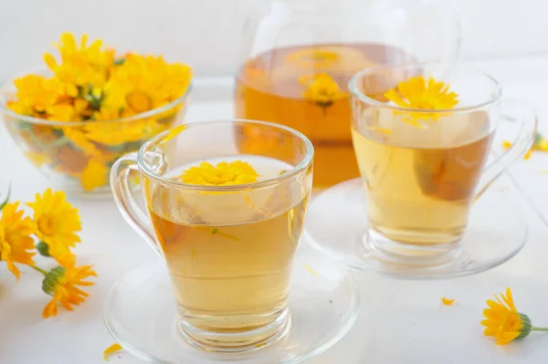 Two cups of healthy marigold tea and calendula flowers in a glass bowl — Stock Photo, Image