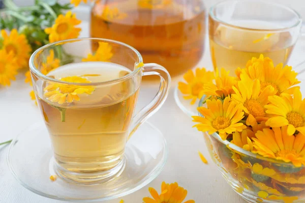 Two cups of healthy marigold tea and calendula flowers in a glass bowl — Stock Photo, Image
