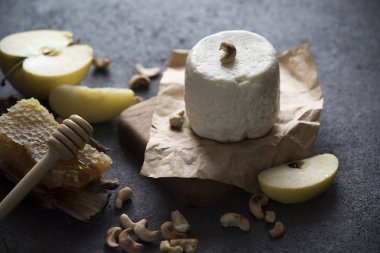 yumuşak peynir, bal, meyve ve fındık karanlık bir arka plan üzerinde