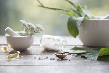 Doğal arka planda muz, otlar, homeopatik granüller ve kapsüller. Alternatif tıp homeopati ve naturopati.