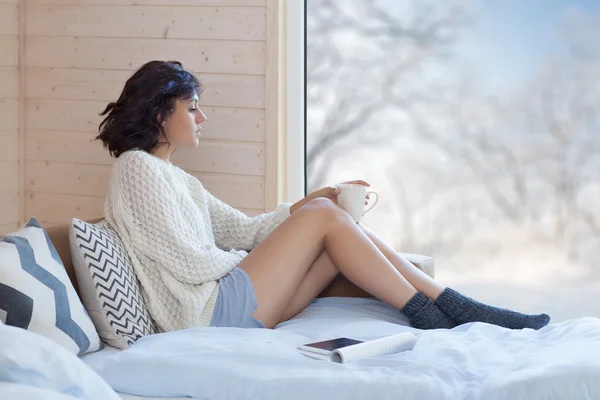 Vrouw met kopje koffie vergadering thuis in de slaapkamer bij het raam — Stockfoto