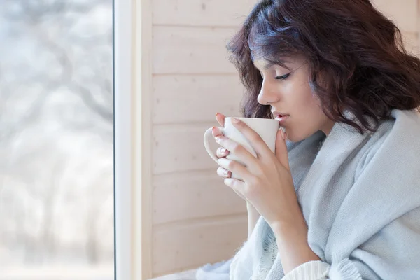 Bela mulher morena coberta de cobertor com xícara de café — Fotografia de Stock