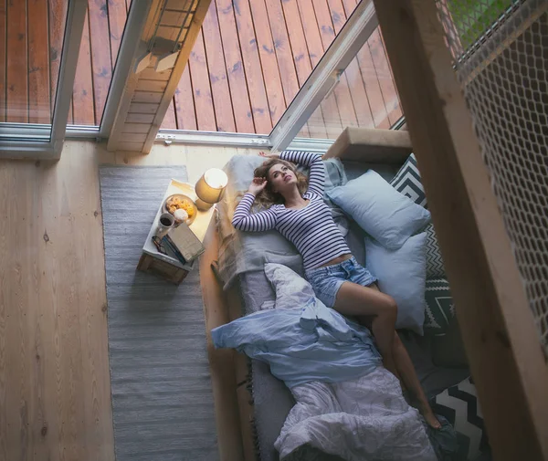 Young Woman Wearing Shorts Lying Bed Window Cozy Wooden Cabin — 스톡 사진
