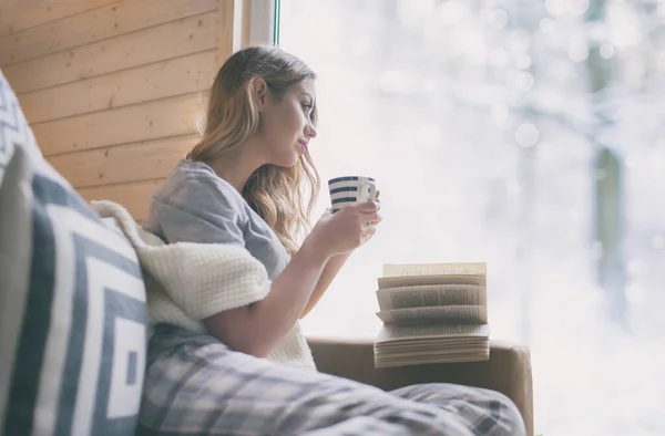 Junge Schöne Blonde Frau Mit Einer Tasse Kaffee Sitzt Hause lizenzfreie Stockfotos