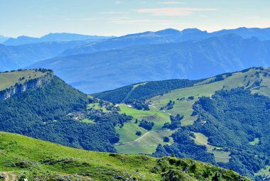 Monte Baldo, yeşil tarlalar ve ormanlarla kaplı dağlar.
