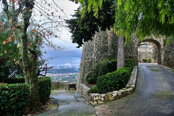 Saint-Paul-de-Vence / Provence - Alpler - Cote d 'Azur, Fransa - tepenin üzerinde yeşil ağaçlar ve çalılar ile güçlendirilmiş bir tepe üzerinde yol, yaz öğleden sonra beyaz-mavi gökyüzü