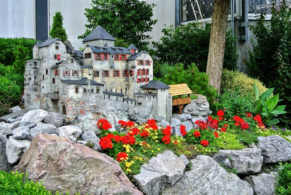 Vaduz, Lihtenştayn - Vaduz Şatosu 'nun küçük bir kopyası, kırmızı ve sarı çiçeklerle süslenmiş, yeşil çalılar altında, yaz öğleden sonra,.