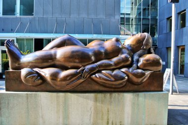 Vaduz, Liechtenstein - 06.26.2014: The sculpture Reclining Woman sleeping on her back is located on a city street, brown made of bronze.