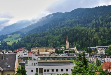 Landeck, Avusturya - Alp dağları yakınlarındaki küçük bir kasabanın panoraması, kilise binasını görebilirsiniz, şehrin yanında yeşil ormanlar, gökyüzünde bir bulut var..