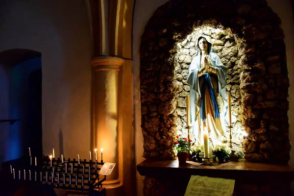 Mondsee, Avusturya - 08.05.2016: Basilika St. Michael 'da mavi pelerinli Bakire Meryem heykeli, yakınlarda mumlar yanıyor.