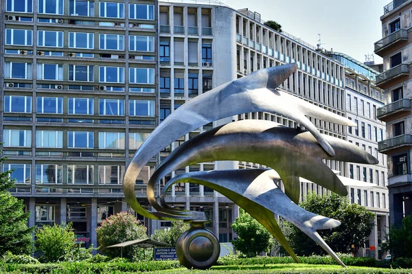 Milan, İtalya - 08.08.2016: İtalya 'daki tüm ölü jandarmaların anısına dikilen Diaz Meydanı' nın fütüristik bir anıtı olan Monumento Ai Carabinieri, arka plandaki yeşil çimenler, arkadaki modern beton binaları andırıyor.