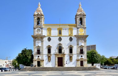 Faro / Algarve, Portekiz - Carmo Kilisesi, sarı renkli beyaz bir bina, kilisenin önüne geçiyor ve Calzada Portekiz 'in kaldırımlarını döşüyor, mavi gökyüzü, yaz aylarında. 