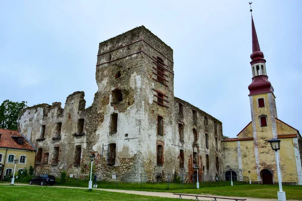 Poltsamaa, Estonya - Yıkılmış taş kale Oberpalen (Poltsamaa), hemen yanında sarı çatılı bir kilise ve çan kulesinde bir horoz bulunur..