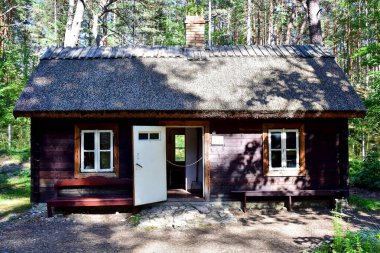 Lielupe / Jurmala, Letonya - Samandan çatılı kahverengi eski ahşap ev, açık beyaz kapı, Jurmala Denizcilik Müzesi, yaz aylarında bir orman.