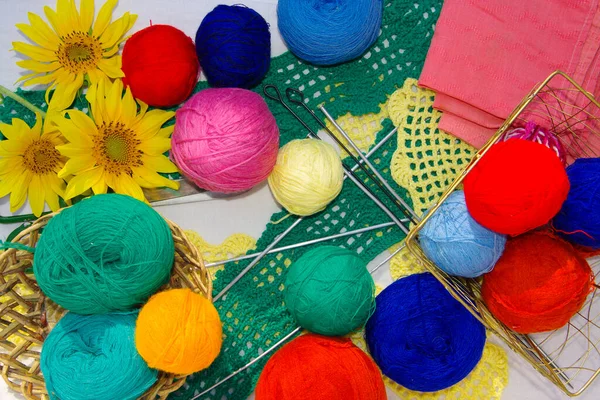 A set for needlework and yellow flowers on the table. Threads in bundles of different colors for knitting.