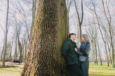 Bir çift güzel sevgi dolu gülümsüyor ve büyük bir ağaç parkta öpüşme.