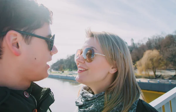 Schöne einander liebende Paar steht auf der Brücke lächelnd und küssend. — Stockfoto