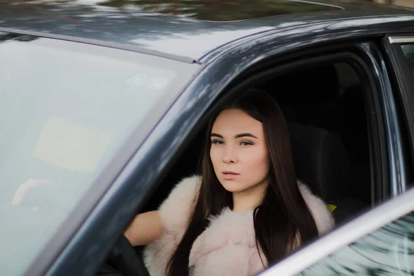 Retrato de uma menina muito bonita em uma floresta vestida de pele em um carro — Fotografia de Stock