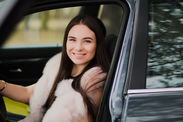 Ritratto di una bellissima ragazza in un bosco vestita di pelliccia in macchina — Foto Stock