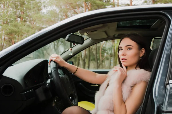 Çok güzel bir kız bir arabada Kürk giymiş bir ormandaki portresi — Stok fotoğraf