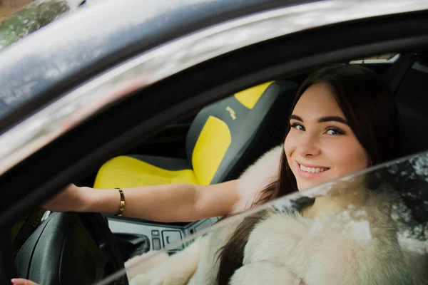 Ritratto di una bellissima ragazza in un bosco vestita di pelliccia in macchina — Foto Stock