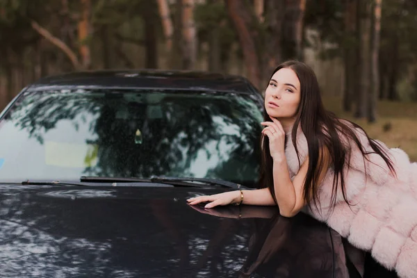 Portret van een heel mooi meisje in een forest gekleed in bont in een auto — Stockfoto