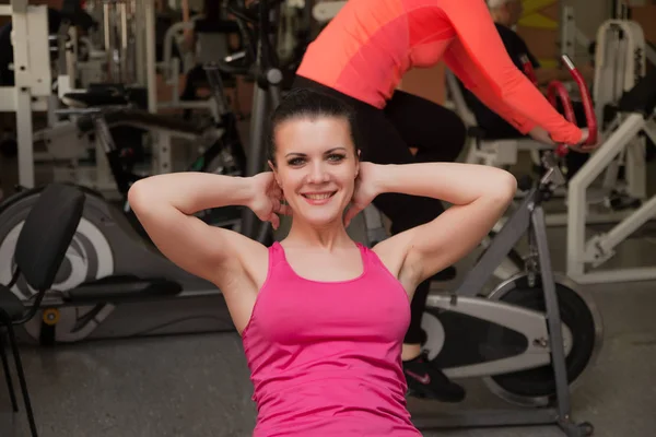 Vacker flicka coachar en press i ett gym. — Stockfoto