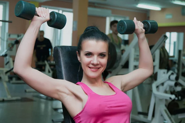 Hermosa chica haciendo ejercicio en el gimnasio con mancuernas . —  Fotos de Stock