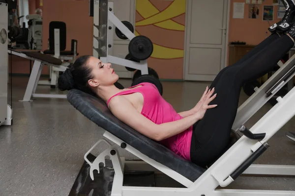 Hermosa chica entrenando piernas en el club de fitness — Foto de Stock