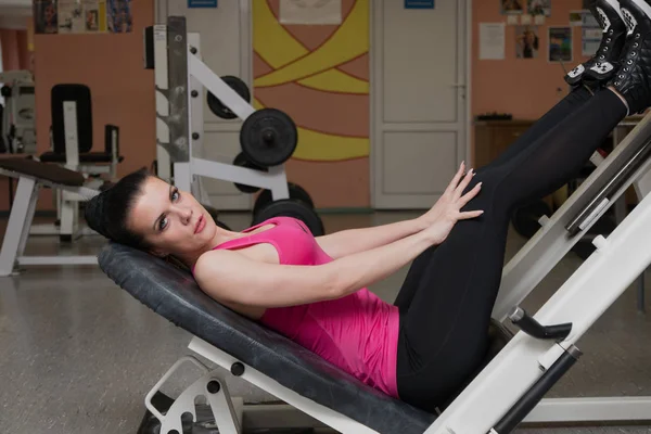 Hermosa chica entrenando piernas en el club de fitness —  Fotos de Stock