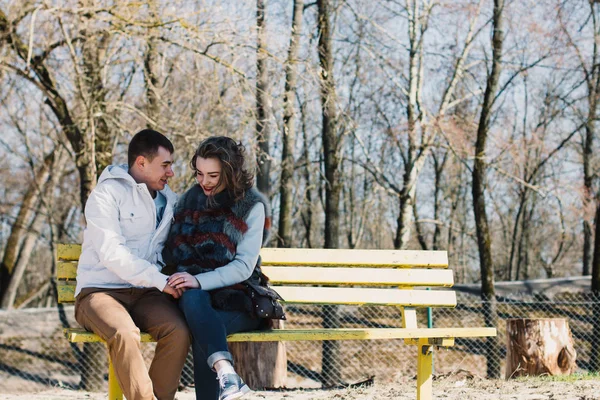 Pareja feliz enamorada abrazando y compartiendo emociones, tomados de la mano en un banco junto al río — Foto de Stock