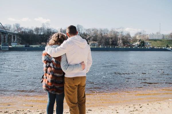 Happy couple in love hugging and sharing emotions, holding hands on the river bank — Stock Photo, Image