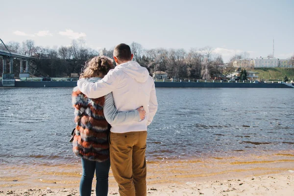 Pareja feliz enamorada abrazando y compartiendo emociones, tomados de la mano en la orilla del río — Foto de Stock