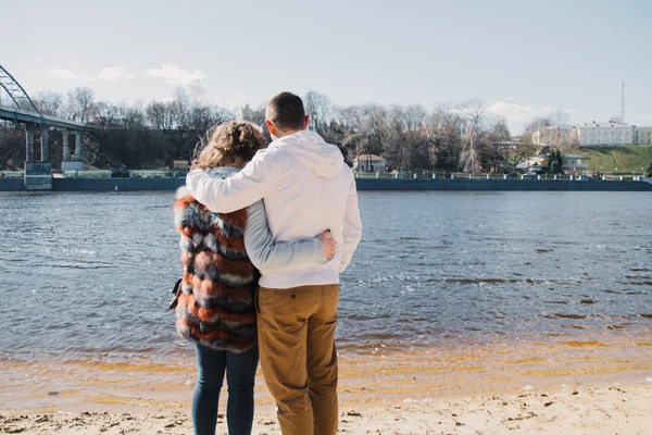 Pareja feliz enamorada abrazando y compartiendo emociones, tomados de la mano en la orilla del río — Foto de Stock