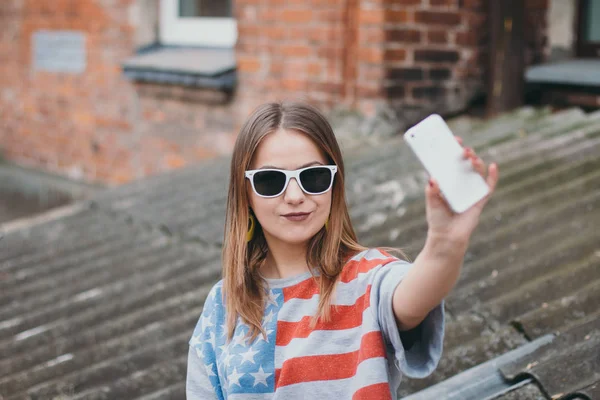Uma garota mais moderna em um antigo pátio com um telefone faz uma selfie — Fotografia de Stock