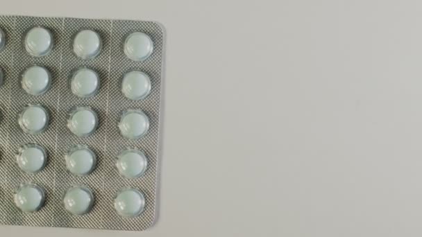 Медицинские таблетки помещены на вращающийся стол, снятый с белым бесшовным фоном — стоковое видео
